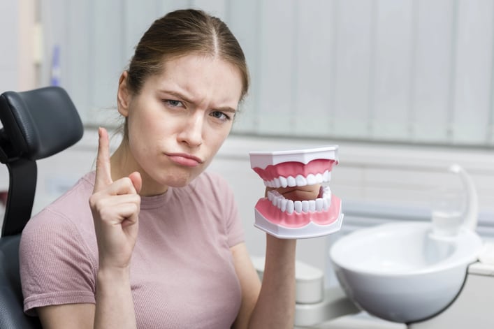 portrait-adult-woman-holding-toy-teeth-min